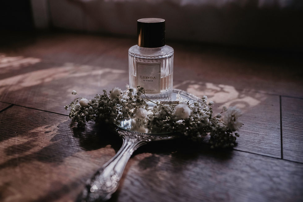 wedding details of perfume, floral hair pieces sittin on antique silver mirror