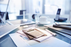 Desk with paper, pen, calculator and phone