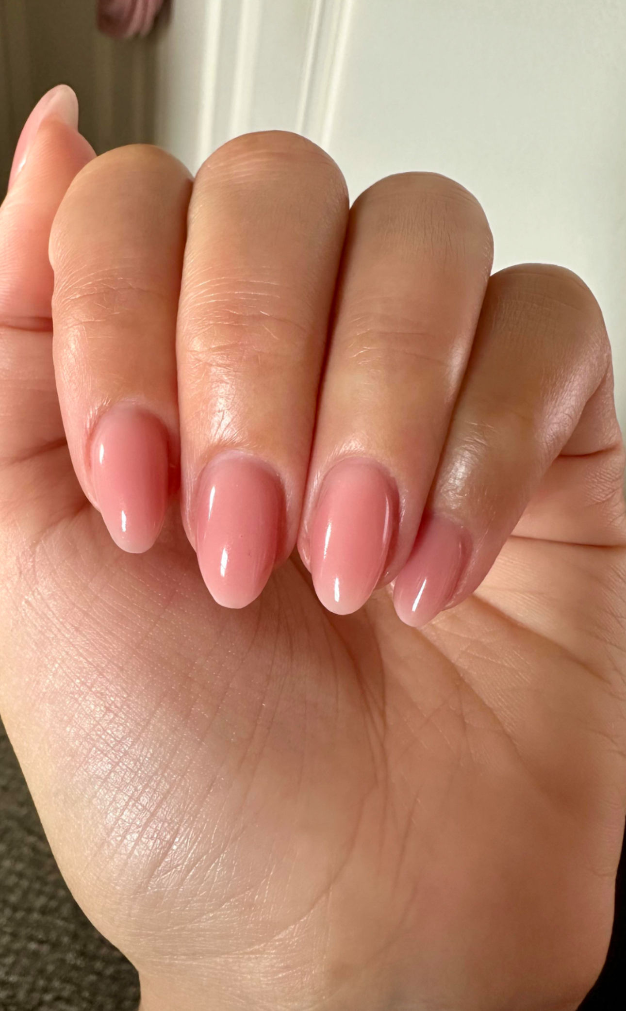 Hands with red nail polish hold a blue dropper bottle with a gold cap, set against a neutral background. The scene conveys elegance and care.