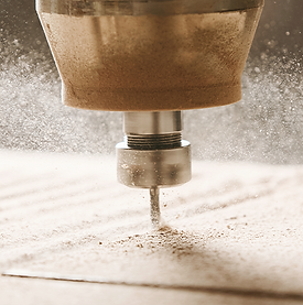 CNC router milling out a sheet of light wood with dust flying.