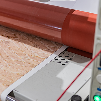Large heat commercial laminator laminating a paper print.