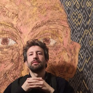 Ali Omar with portrait work in the background