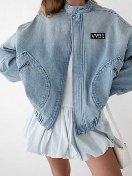 oversized light blue denim jacket from VYBE over a white dress, paired with a minimal shoulder bag.