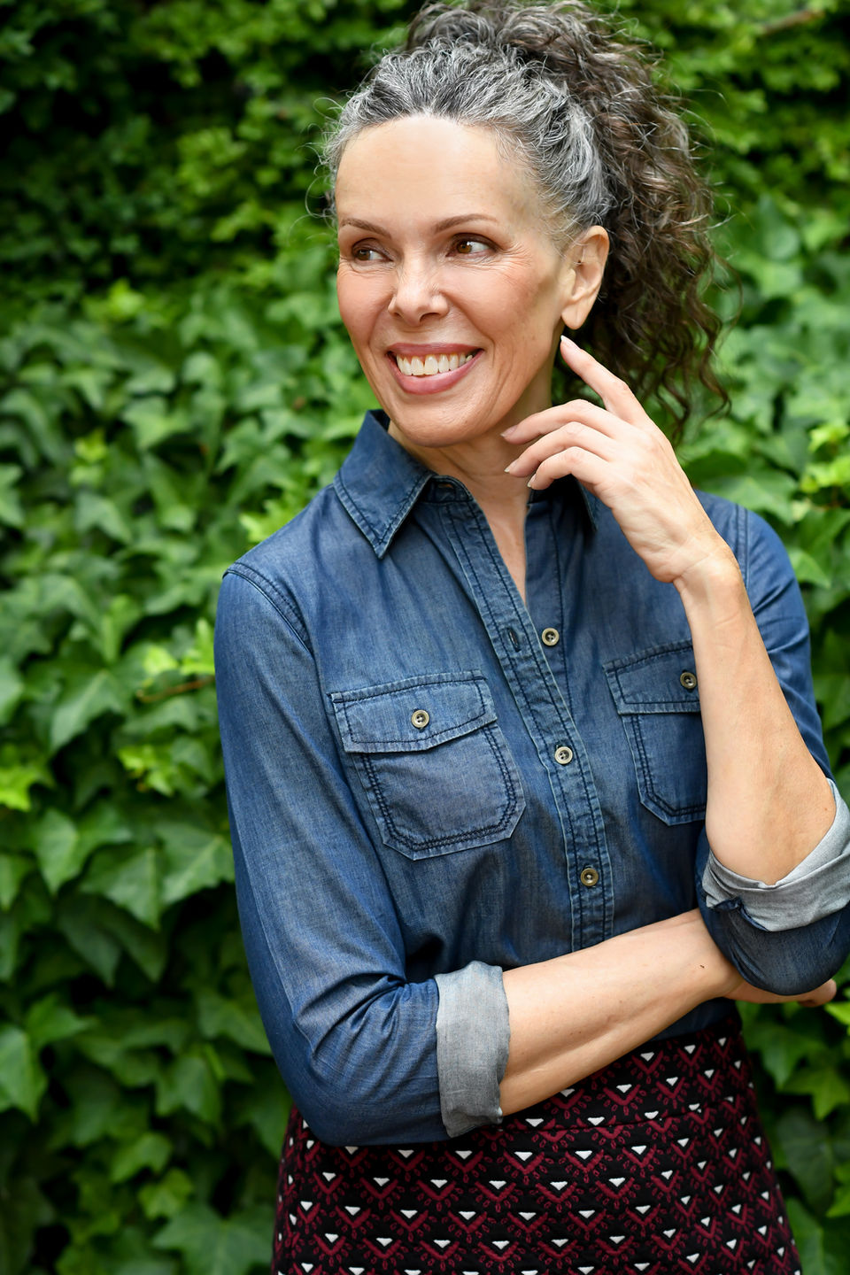 Lifestyle model in denim shirt standing in front of hedge