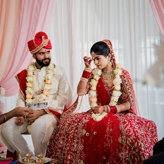 Bride and groom seated together beneath mandap during Hindu wedding ceremony