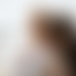 Groom embraces bride from behind at sunset along the NYC waterfront, capturing a quiet moment of calm before their multicultural wedding celebration.