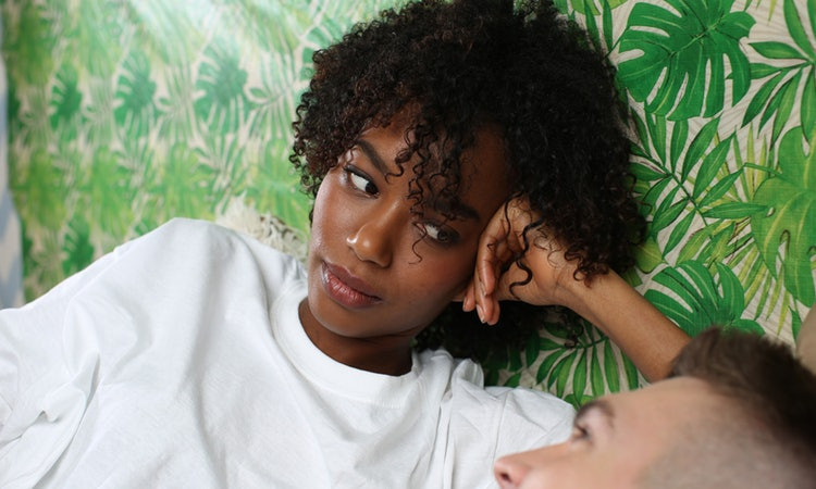 Black woman looking at white man in bed