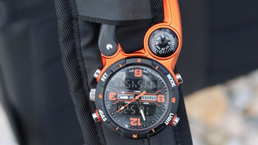 Orange and black watch with a digital display and compass, attached to a black fabric strap. The watch face shows time and features labeled controls.
