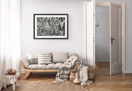 a framed picture of a leopard on a wall above a couch titled 'Silent Grace'