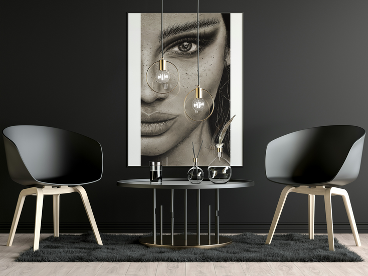 a black and white painting of a woman 's face hangs above a table