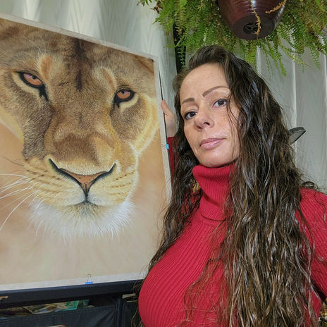 artist posing with lioness artwork nearly finished, fine details and textures being added.