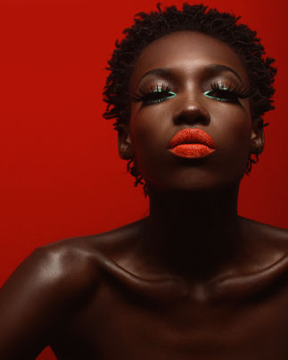Fotografia de beauty por Du Borsatto mostrando modelo negra Rojane Fradique com batom vermelho vibrante e iluminação de estúdio em fundo vermelho.