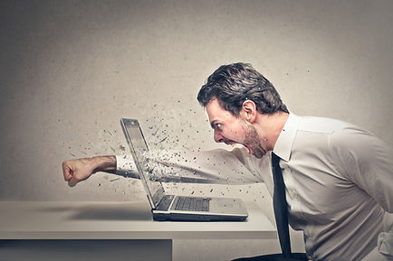 furious businessman throws a punch into the computer.jpg