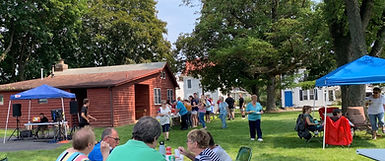 People enjoying an outdoor pot-luck picnic on the lawn