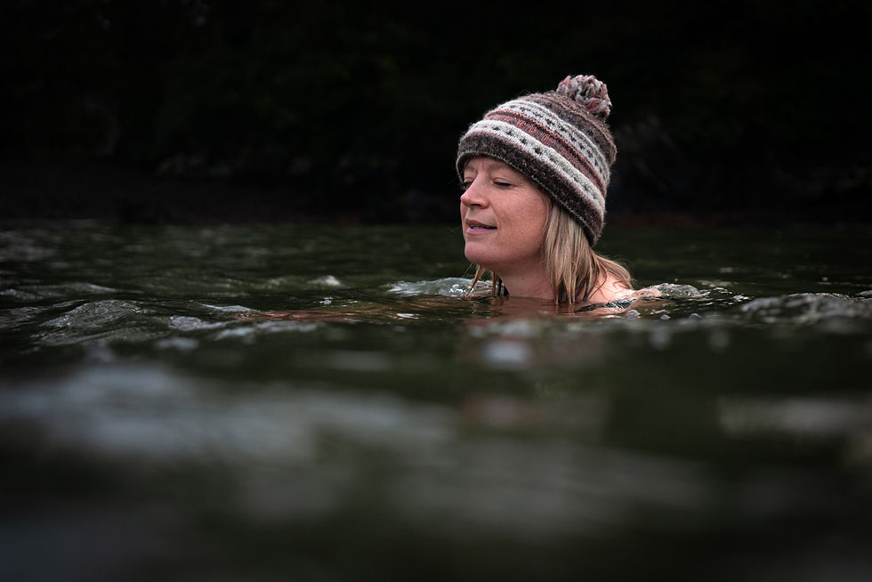 A woman wearing a hat swimming in the river looking peaceful
