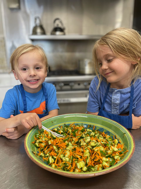 Young campers smiling while mixing or preparing food.