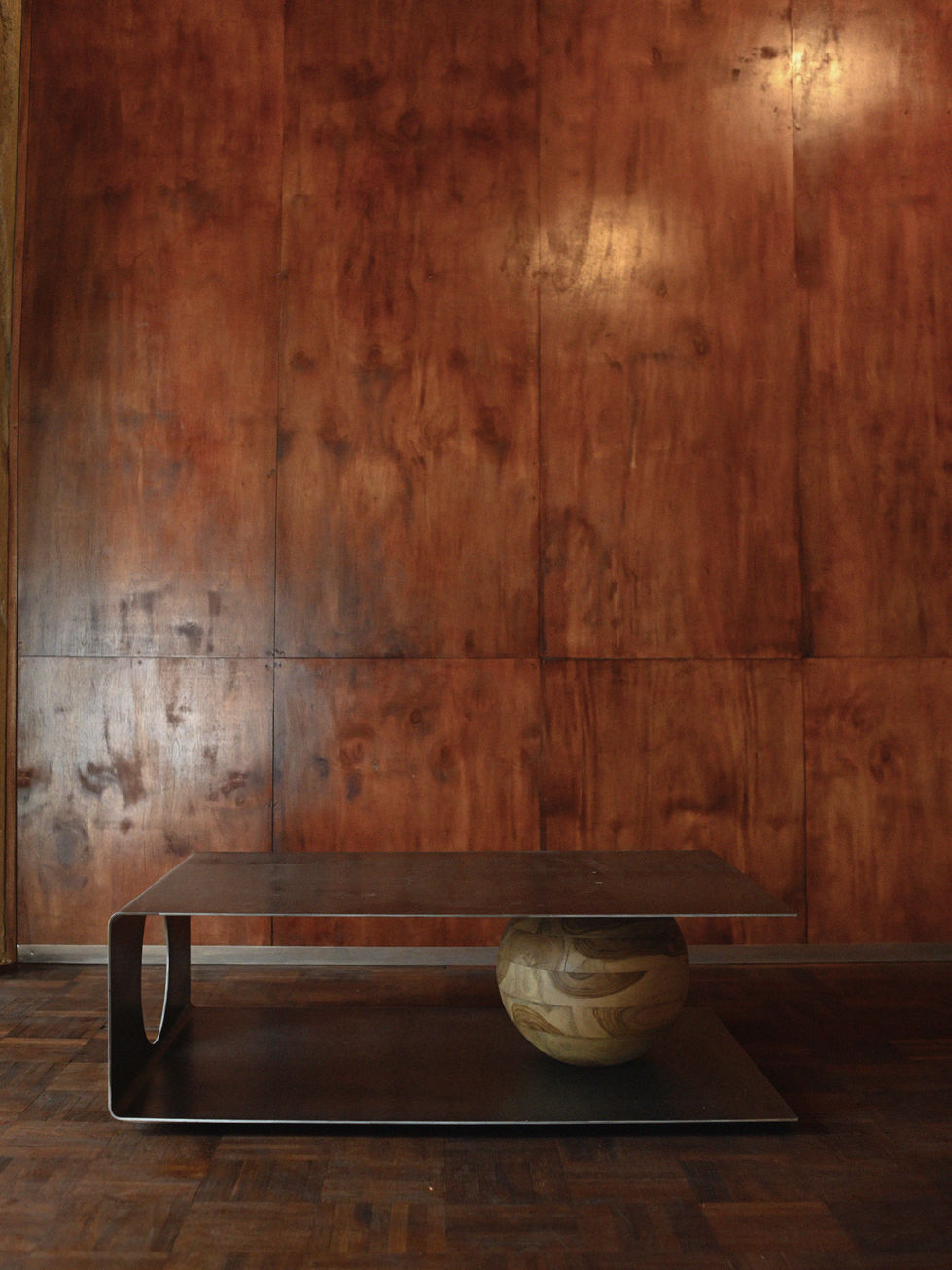 Sculptural coffee table crafted from raw hot-rolled steel with a solid laurel wood sphere support in a minimalist architectur
