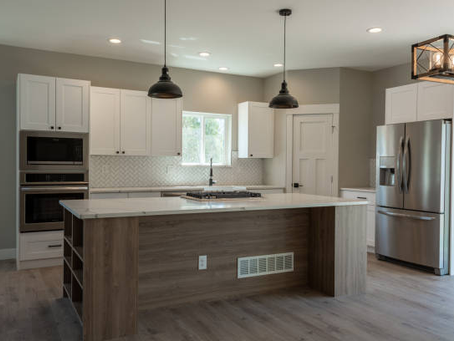 A couple stands in a modern kitchen featuring a microwave, showcasing a renovation by a kitchen renovation company.