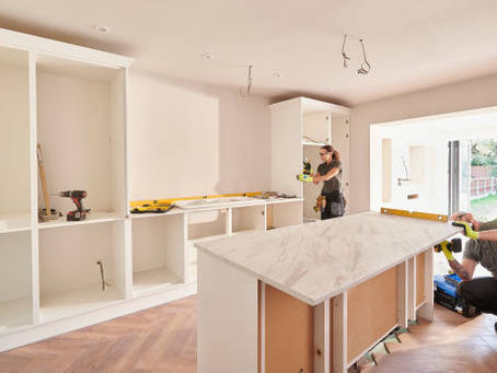 A man and woman work together in a kitchen, planning details for a custom home renovation.