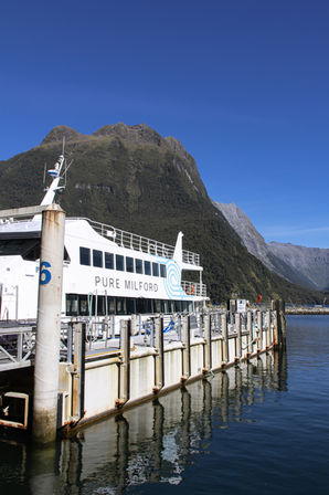 Ausflugsboot von Pure Milford am Anleger vor der beeindruckenden Berglandschaft des Milford Sound