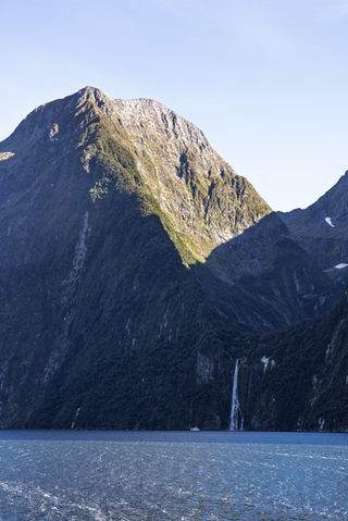 Hohe Bergflanke und Wasserfall am Milford Sound während der Bootsfahrt durch den Fiordland Nationalpark.