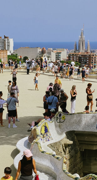 Blick vom Park Güell über Barcelona bis zur Sagrada Família und zum Mittelmeer an einem sonnigen Tag.