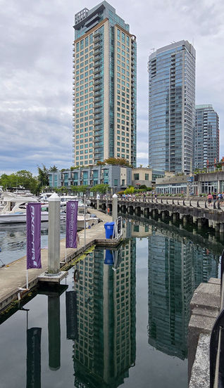 Hochhäuser spiegeln sich im Wasser des Coal Harbour an der Uferpromenade von Vancouver
