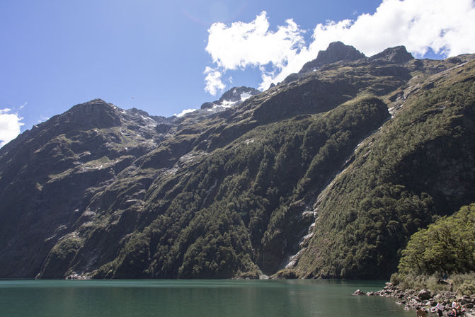 Steile bewaldete Berghänge erheben sich direkt über dem Lake Marian im Fiordland Nationalpark.