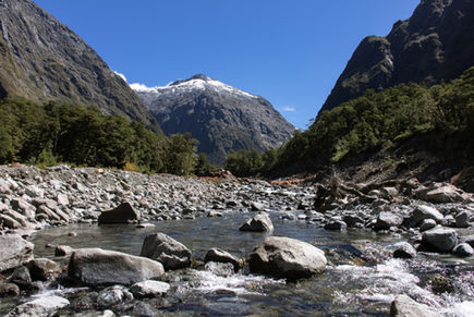 Monkey Creek fließt durch ein felsiges Tal unter schneebedeckten Bergen im Fiordland Nationalpark