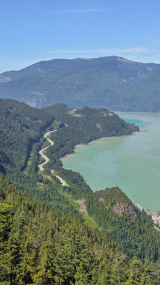 Luftaufnahme des kurvigen Sea to Sky Highway entlang des Howe Sound, umgeben von dichter Berglandschaft