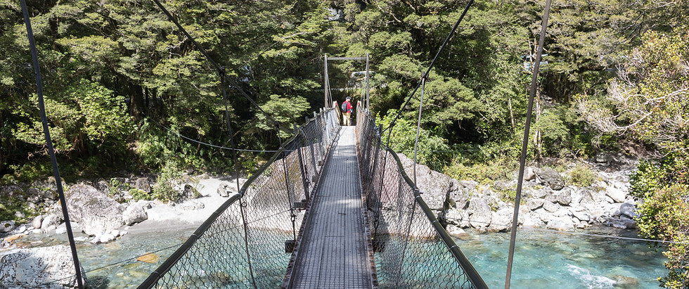 Hängebrücke über einen klaren Gebirgsfluss am Lake Marian Track im Fiordland Nationalpark in Neuseeland.