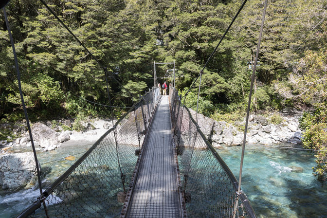 Hängebrücke über einen klaren Gebirgsfluss am Lake Marian Track im Fiordland Nationalpark in Neuseeland.