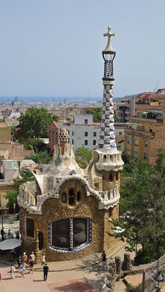 Pförtnerhaus und Turm im Park Güell mit kunstvollen Mosaiken und mediterraner Stadtkulisse in Barcelona.
