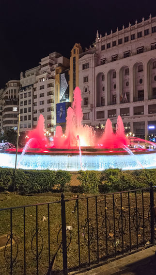 Rot und weiß beleuchteter Springbrunnen auf der Plaza del Ayuntamiento im nächtlichen Zentrum von Valencia.
