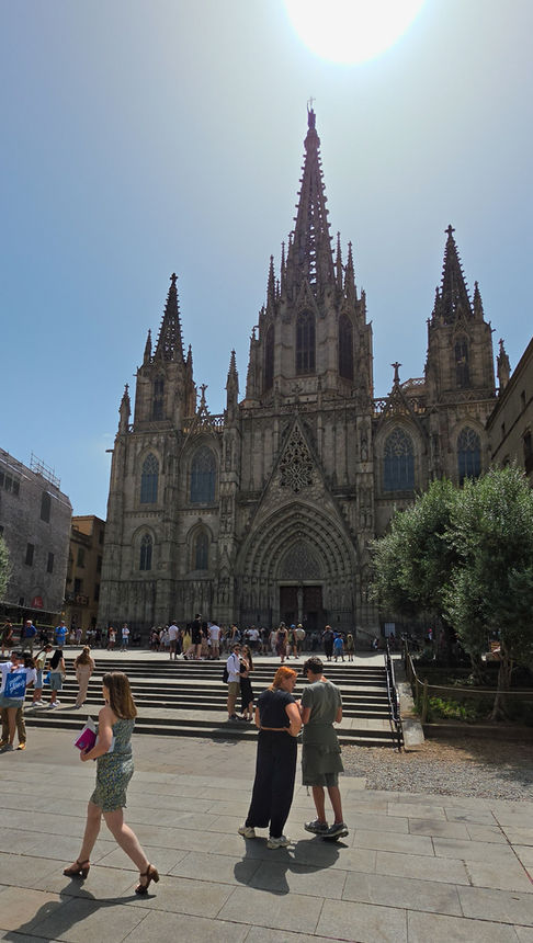 Außenansicht der Kathedrale von Barcelona mit imposanter gotischer Fassade und Besuchern auf dem Vorplatz.