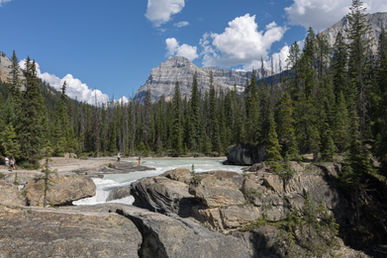 Natural Bridge im Yoho National Park mit kraftvollem Fluss, Felsenformationen und Bergkulisse bei Sonnenschein