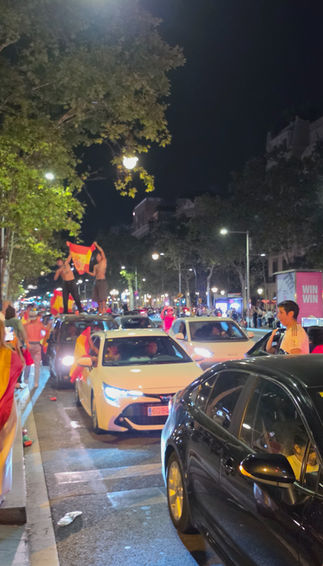 Autokorso mit spanischen Flaggen und feiernden Fans in der Innenstadt von Barcelona bei Nacht.