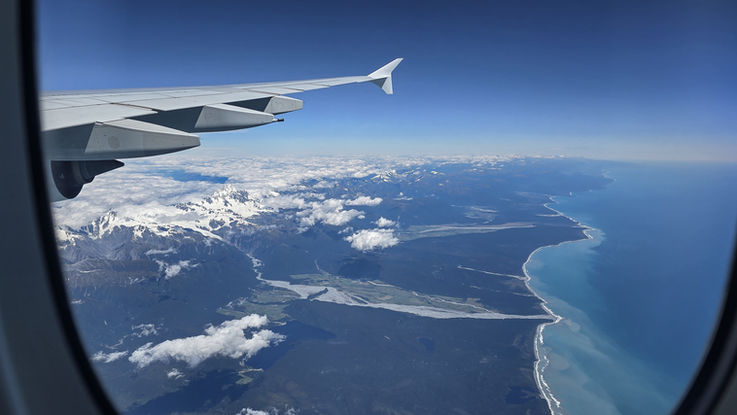 Atemberaubender Blick aus dem Flugzeug auf den schneebedeckten Mount Cook und die Küste Neuseelands.