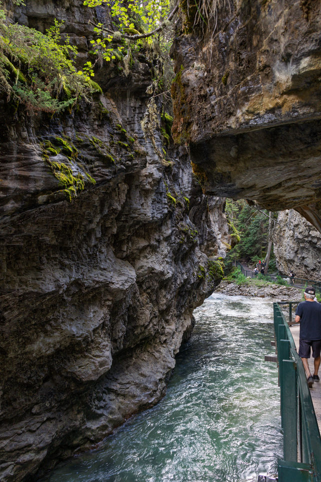 Dramatischer Blick unter einen Felsüberhang entlang des Stegs im Johnston Canyon.