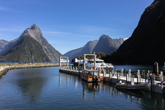 Bootsanleger am Milford Sound mit Ausflugsbooten und markanter Bergkulisse im Fiordland Nationalpark