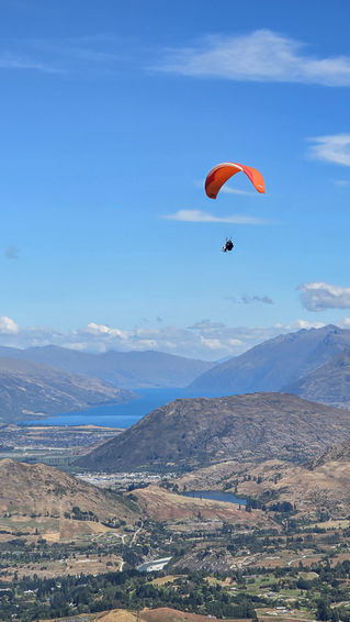 Gleitschirmflieger über der Berglandschaft am Coronet Peak mit Blick Richtung Queenstown in Neuseeland