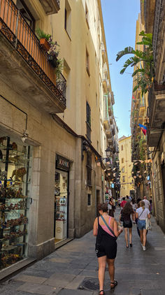 Schmale Gasse im Barri Gòtic in Barcelona mit historischen Fassaden, kleinen Geschäften und Fußgängern.