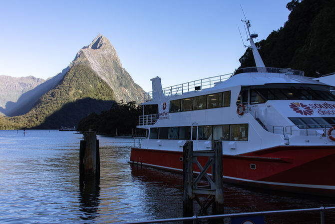 Ausflugsschiff von Southern Discoveries am Anleger im Milford Sound vor der eindrucksvollen Bergkulisse.