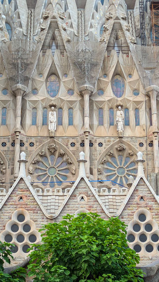 Detail der Außenfassade der Sagrada Família mit Rosettenfenstern, Skulpturen und filigranen Gaudí-Elementen.