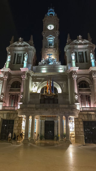 Nächtliche Frontansicht des Rathauses von Valencia mit beleuchtetem Uhrturm an der Plaza del Ayuntamiento.