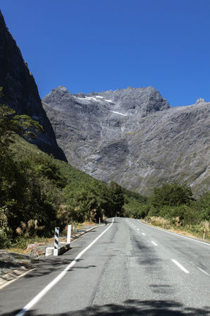 Milford Road führt unter steilen Felswänden und alpinen Gipfeln durch den Fiordland Nationalpark