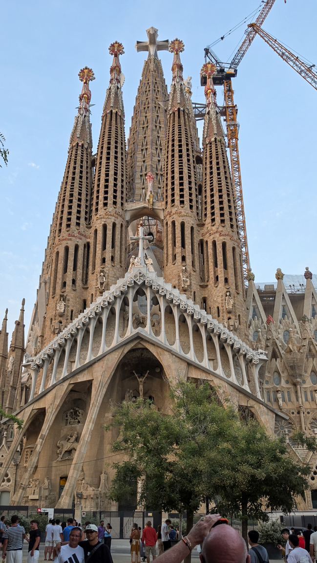 Frontaler Blick auf die Passionsfassade der Sagrada Família mit monumentalen Türmen und Kreuz in Barcelona.