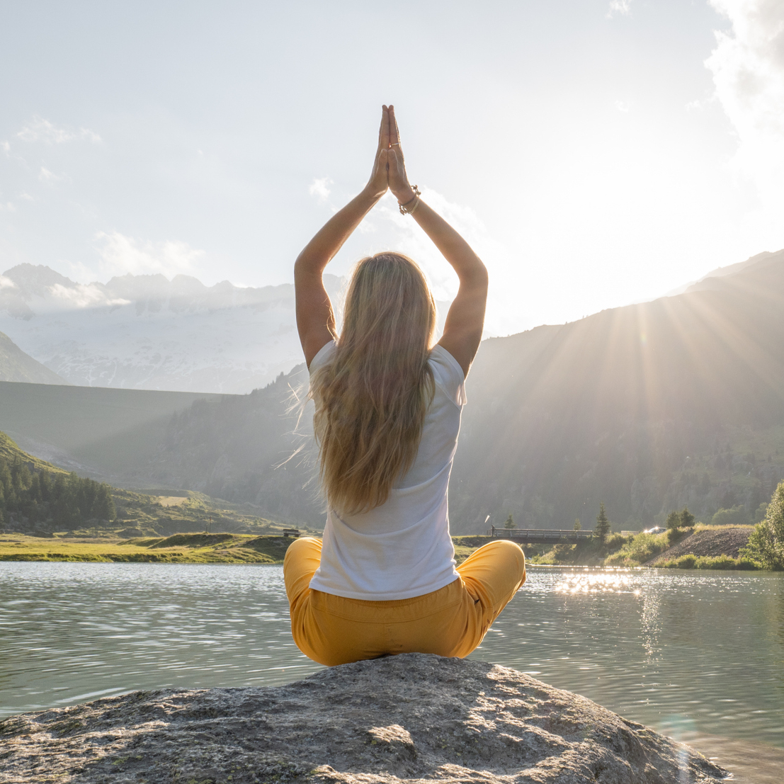 Woman meditating by a mountain lake