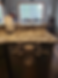 Kitchen with granite countertop, folded towels on dishwasher handle, paper towels in holder. Dining table by window in background.