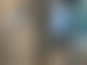 Modern bathroom with a glass shower, gray tile walls, leafy-patterned wallpaper, and organized toiletries. Bright light from window.